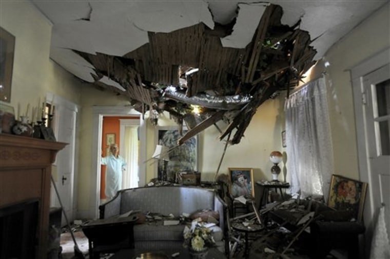 Frances Lukens looks at the tangle of boards and tree limbs piercing her living room ceiling in Lynchburg, Va. on Saturday, June 30, 2012 after a huge oak tree fell directly on the house during a storm the previous night. (AP Photo/The News &amp; Advance, Parker Michels-Boyce)
